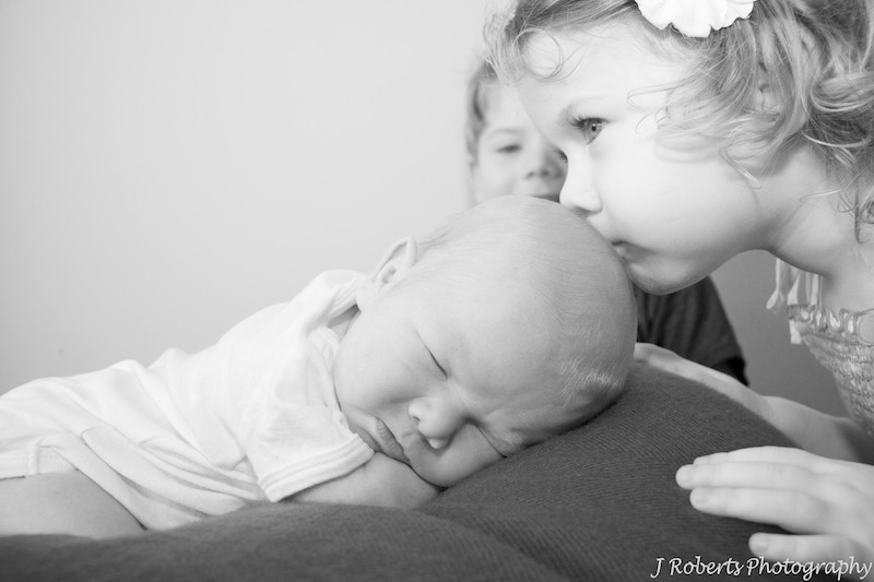 Big sister kissing newborn baby - newborn portrait photography